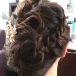 Intricately styled updo with curls and a decorative hair accessory.