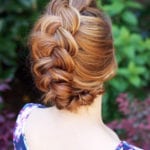 A woman with a neatly braided updo hairstyle.