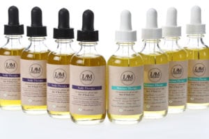 Bottles of hair growth serum with droppers in two sets of different label colors.