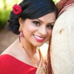 A smiling woman with a red flower in her hair.