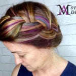 A woman with colorful braided hair styled in an updo.