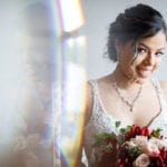 A bride smiling while holding a bouquet of flowers.