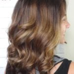 Side view of a woman with wavy brown hair and blonde highlights.