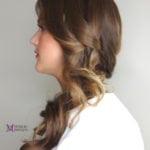Profile view of a woman with styled brown hair in loose curls.
