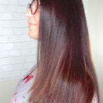 Profile of a woman with long, straight brown hair and glasses.