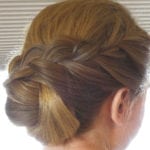 A woman with blonde hair styled in a braided updo.