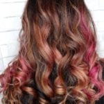 Long wavy hair with shades of brown and pink highlights.