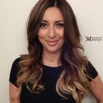 A woman with long, wavy hair smiling at the camera.