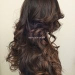 Long wavy brown hair styled in loose curls.