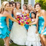 Bridal party with bride and bridesmaids in turquoise dresses holding a colorful bouquet.