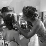 A stylist braiding a woman's hair in a salon.