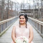 A bride in a white dress holding a bouquet on a wooden bridge.