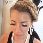 Woman with braided hair and makeup looking down.