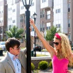 A young boy and girl interacting outdoors near a lamp post.