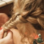A close-up of hands braiding curly hair.