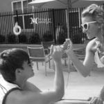 A man proposes to a woman by the poolside.