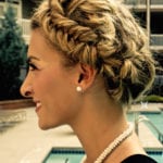 Profile of a smiling woman with braided hair and pearl earrings.