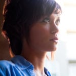 A close-up of a woman with short hair looking thoughtfully to the side.