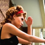 A woman with a red headband looking thoughtfully out a window.