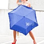 A person holding a blue umbrella with white text.