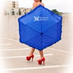 Woman holding a blue umbrella, wearing red high heels.