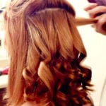 A person having their hair curled with a curling iron.