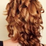 Close-up of shiny, curly auburn hair.