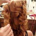 A person styling curly, reddish-brown hair.