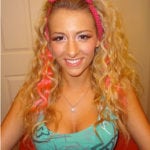 A smiling woman with curly blonde hair and pink streaks.