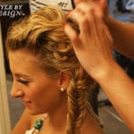 A woman having her hair braided into a fishtail style.