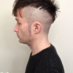 Profile of a young man with a unique haircut featuring shaved sides and longer hair on top.