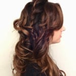 Side view of a woman with styled, curled brown hair.