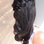A woman with long, wavy black hair styled in a half-up braid.