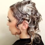 Side profile of a woman with short wavy, silver and brown hair.
