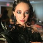 A woman with dramatic makeup and a feathered black outfit.