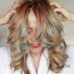 A woman with multicolored hair covering her face.