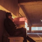 Person sitting on the ground in a dimly lit parking garage.