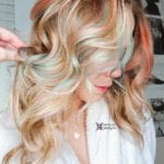A woman with long, wavy blonde hair styled in loose curls.