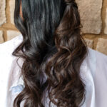 Long dark hair with loose curls and a small braid.