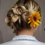 A braided hairstyle adorned with a yellow sunflower.