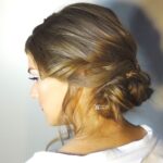 Side view of a woman with a styled low bun and soft waves.