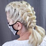 Side view of a woman with intricately braided blonde hair wearing a face mask.