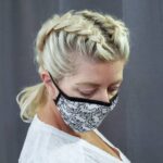 Woman with blonde hair and braided hairstyle wearing a black and white patterned face mask.