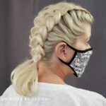 Woman with blonde braided hair wearing a black and white face mask.