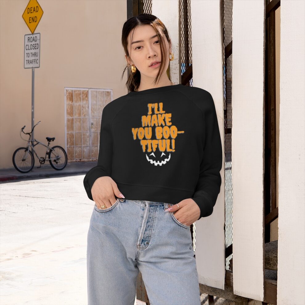 A young woman wearing a black sweatshirt with a yellow graphic and light blue jeans, standing against an urban backdrop with a bicycle and street signs.