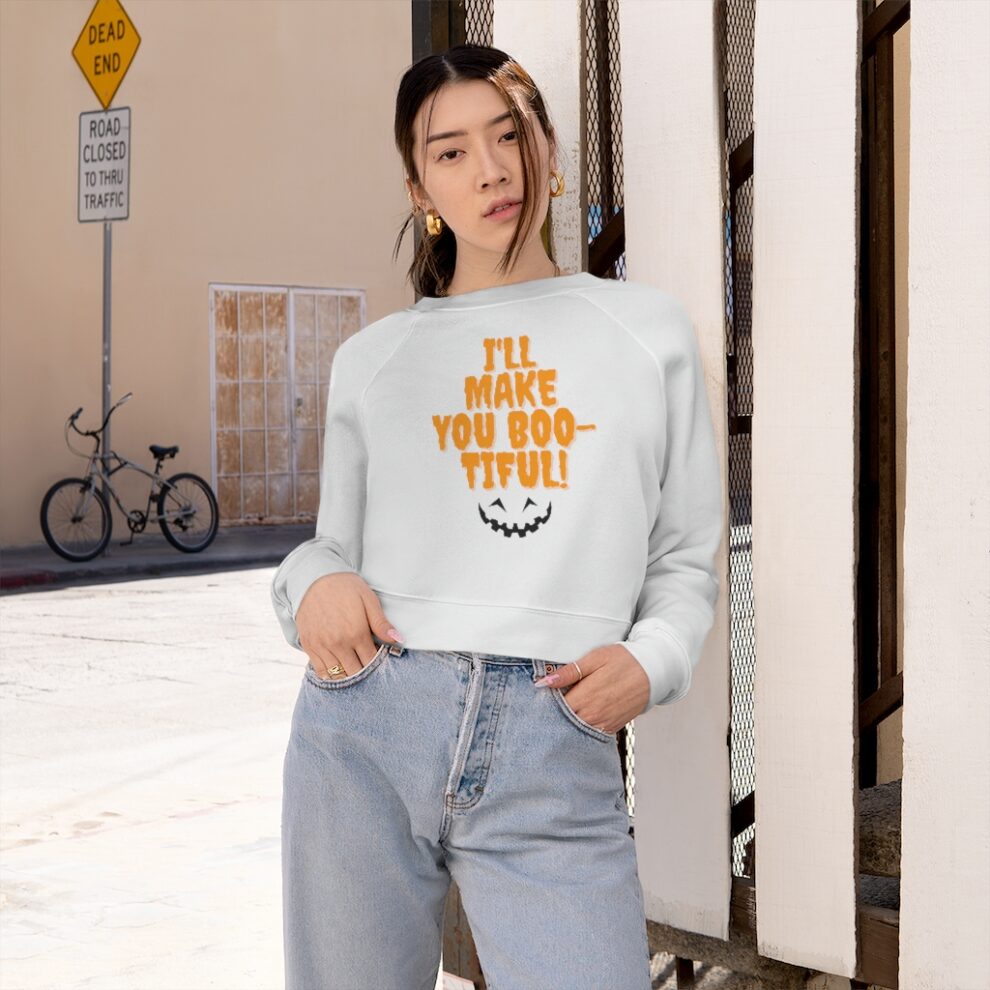 A woman standing in front of a building wearing jeans and a sweatshirt.