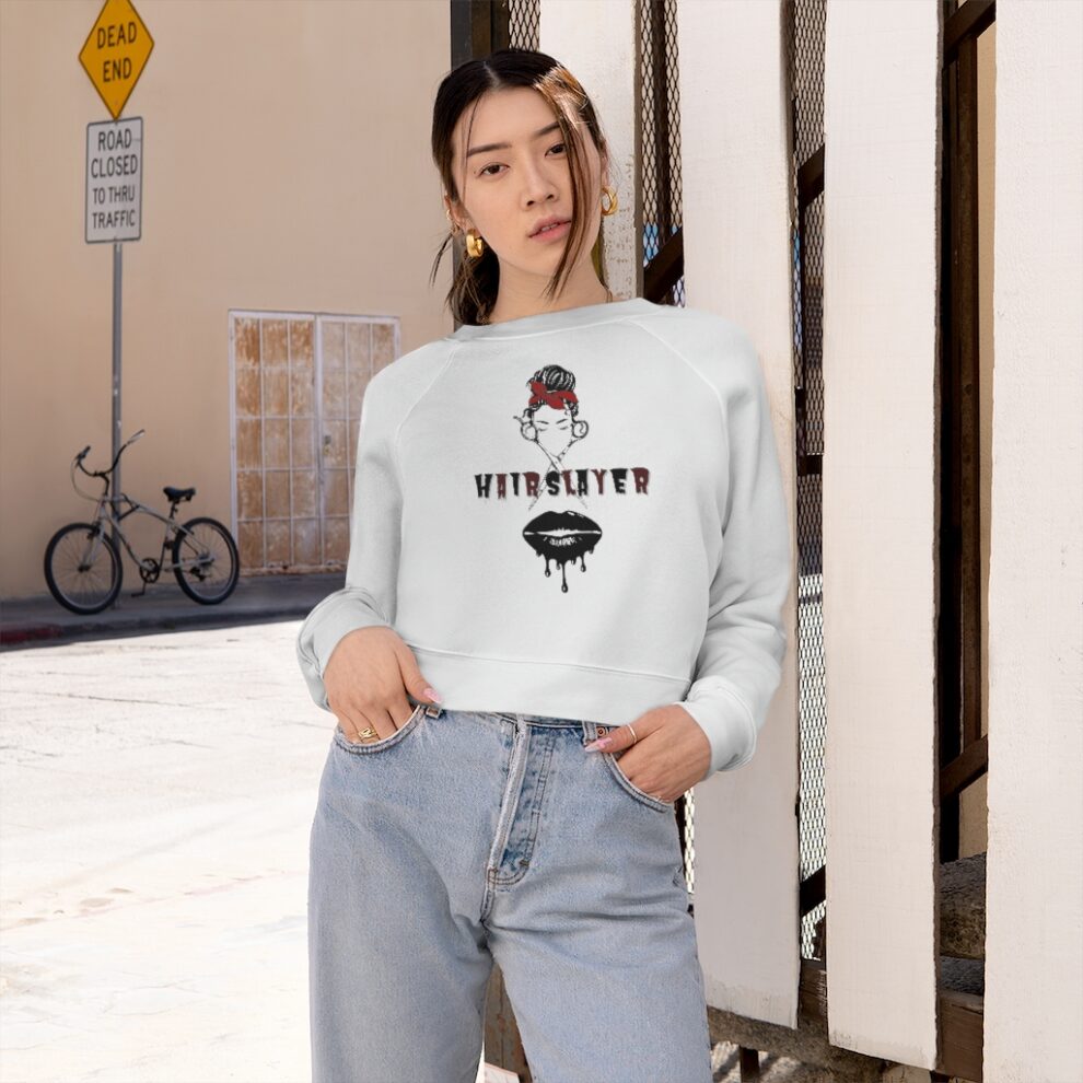 A woman standing on the sidewalk wearing jeans and a sweatshirt.