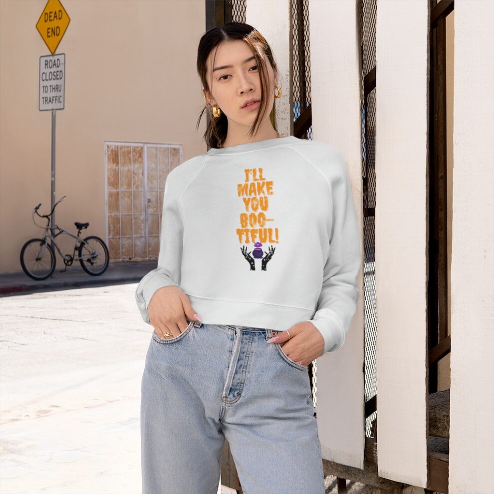 A woman standing on the sidewalk wearing jeans and a sweatshirt.