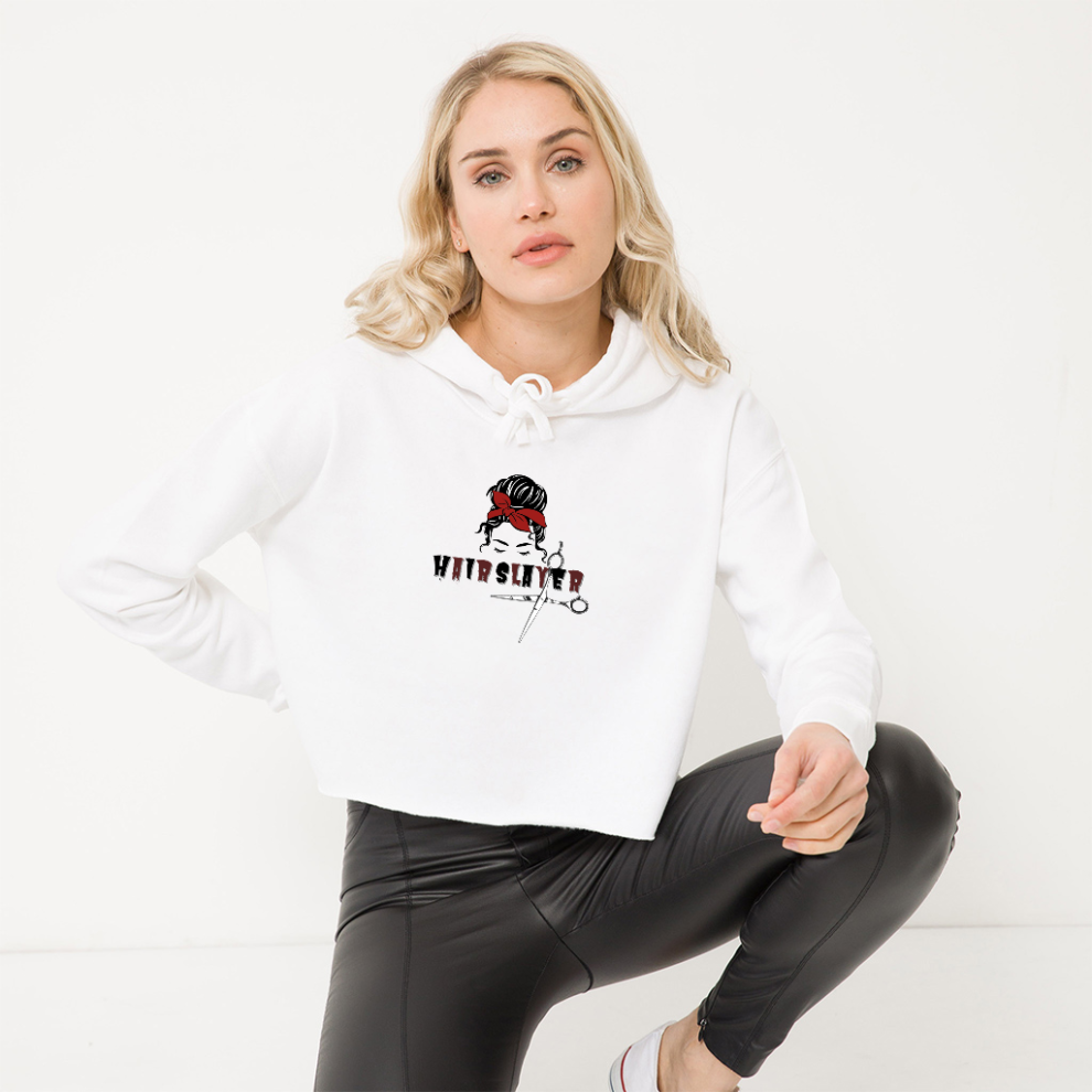 A woman sitting on the ground wearing white pants and a hoodie.