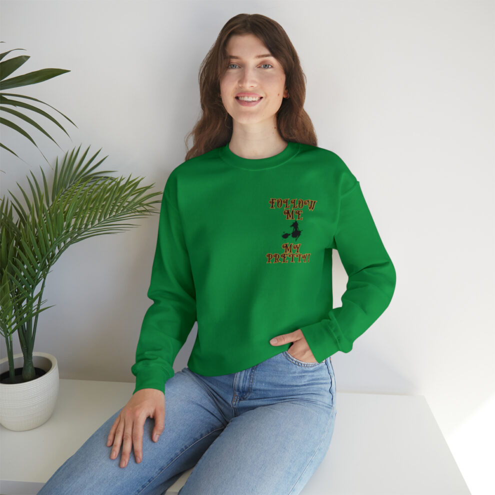 A woman sitting on the ground wearing jeans and green sweatshirt.